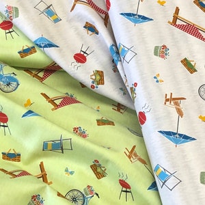 May include: Two fabric swatches with a repeating pattern of picnic-themed imagery. The top swatch is white with a light gray background and features images of umbrellas, picnic baskets, and chairs. The bottom swatch is a light green with a white background and features images of grills, picnic baskets, and chairs.