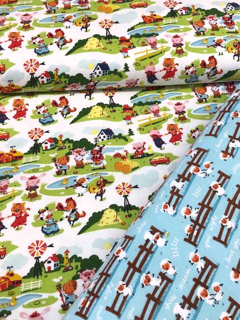 May include: A white fabric with a repeating pattern of farm animals, houses, and windmills. The fabric is blue and white with a repeating pattern of sheep with the text "good night", "sleep", "three dream", "L1ZZZZ", "you", "I love you", and "Zzzz".