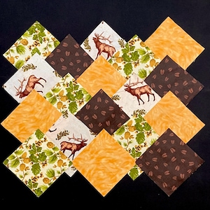 May include: A set of 12 fabric squares featuring a variety of patterns, including a brown and white elk print, a brown and white paw print, and a green and white floral print. The squares are arranged in a diamond pattern.