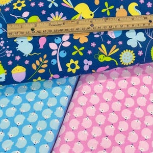 May include: Two fabric swatches with different patterns. The top swatch is blue with a variety of colorful animals, flowers, and insects. The bottom swatch is pink with a repeating pattern of white hedgehogs.