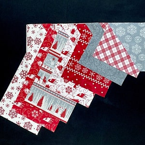 May include: A set of eight fabric squares featuring a winter holiday theme. The squares are in shades of red, white, and gray with patterns of snowflakes, reindeer, and trees. The word "JOY" is printed on one of the squares.