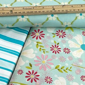 May include: Two pieces of fabric, one with a white and blue striped pattern and the other with a light blue background and a floral pattern with pink, red, and yellow flowers.
