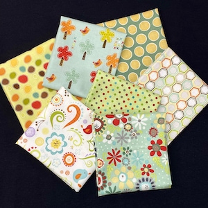Könnte beinhalten: Ein Set aus 10 Stoffquadraten mit verschiedenen Mustern, darunter Punkte, geometrische Formen und Blumenmuster. Die Stoffe sind in Grün-, Gelb- und Brauntönen gehalten.
