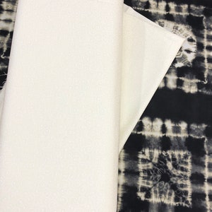 May include: Two pieces of fabric, one white with a small white swirl pattern and one black with a white tie-dye pattern.