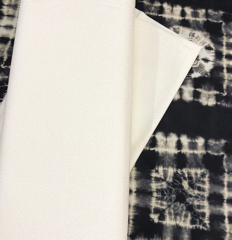 May include: Two pieces of fabric, one white with a small white swirl pattern and one black with a white tie-dye pattern.