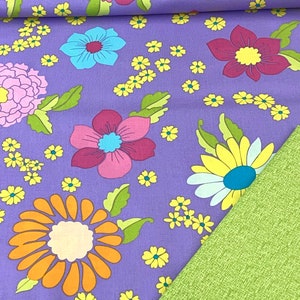 Puede incluir: Tela morada con un patrón repetitivo de flores de colores. La tela tiene una tela verde debajo.