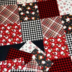 May include: A patchwork of fabric squares in various patterns and colors. Designs include black and white gingham, red and black buffalo plaid, red and white snowflakes, and snowmen. The fabrics are arranged in a quilt-like design.