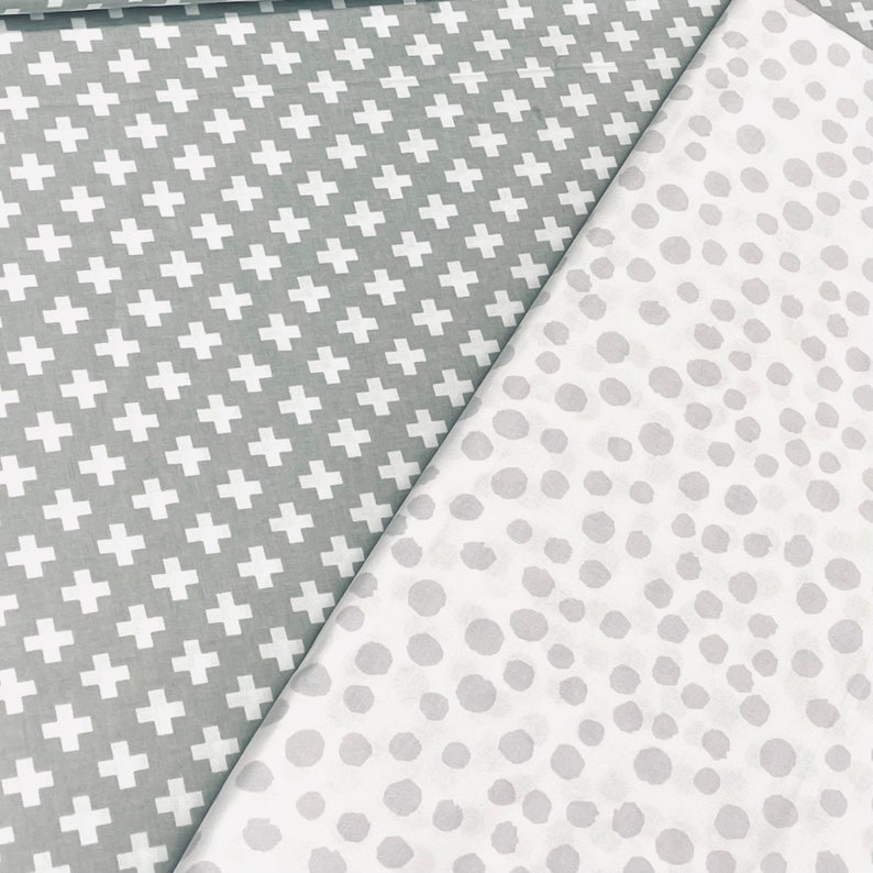 Puede incluir: Dos muestras de tela, una con un patr&oacute;n de cruces blancas sobre fondo gris, y la otra con un patr&oacute;n de lunares blancos sobre fondo gris.