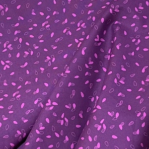 May include: Purple fabric with a repeating pattern of pink seed-like shapes.