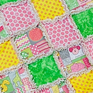 May include: A patchwork baby quilt with a variety of colorful fabrics and patterns. The quilt features a pink, yellow, and green color scheme with a variety of animal designs, including a giraffe, a whale, and a monkey. The quilt is made with a soft, cuddly fabric and is perfect for a baby's nursery.