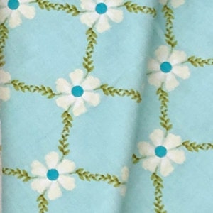 May include: A light blue fabric with a white floral pattern. The flowers have a blue center and are surrounded by green leaves.