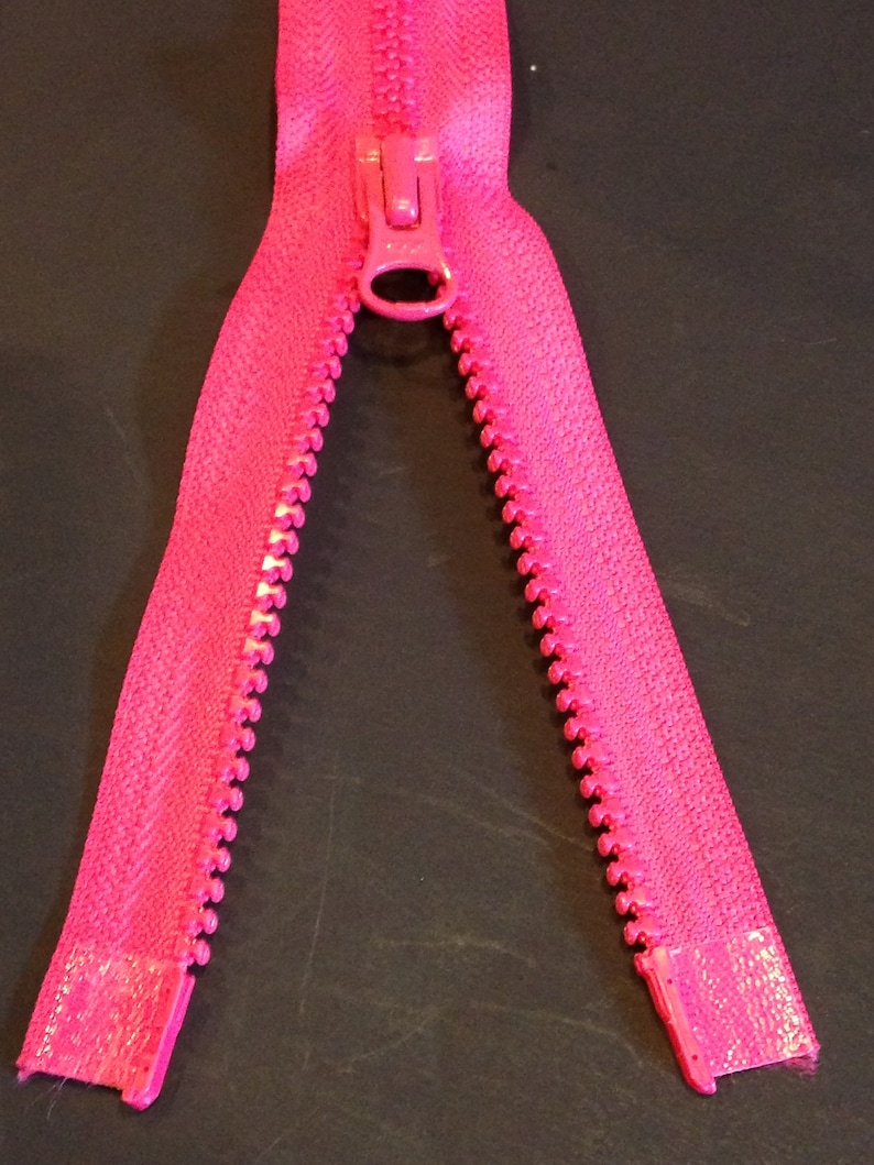 May include: A bright pink zipper with a metal slider. The zipper is open and the teeth are visible.