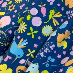 May include: A blue fabric with a repeating pattern of colorful flowers, birds, and other woodland creatures. The fabric is perfect for crafting projects, quilting, and home decor.