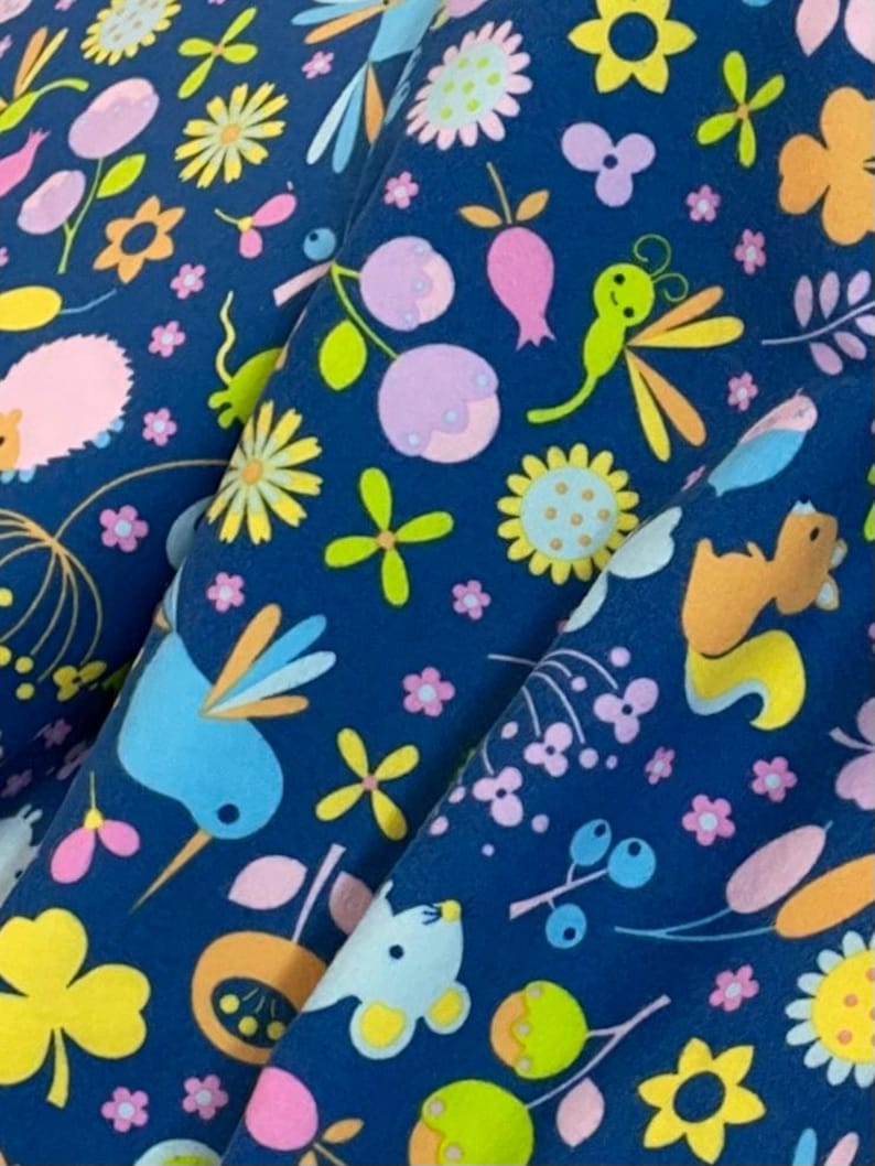 May include: A blue fabric with a repeating pattern of colorful flowers, birds, and other woodland creatures. The fabric is perfect for crafting projects, quilting, and home decor.