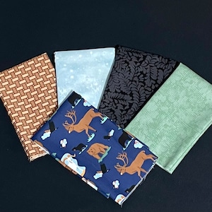 Può includere: Cinque campioni di tessuto diversi, tra cui un motivo intrecciato marrone e beige, un tessuto blu chiaro con un motivo di fiocchi di neve bianchi, un tessuto nero con un motivo a foglie grigio scuro, un tessuto verde chiaro con un motivo testurizzato e un tessuto blu scuro con un motivo di cervi, orsi e uccelli.