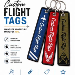 May include: Three rectangular fabric keychains with metal rings, featuring embroidered designs in blue, red, and olive green. The blue tag shows an airplane, the red tag displays wings with a star, and the olive tag depicts mountain peaks.