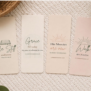 May include: Four rectangular bookmarks with inspirational quotes. The first bookmark is beige with the text "Be Still and know" and Psalm 46:10. The second bookmark is beige with "Grace for today" and 2 Corinthians 12:9. The third bookmark is beige with "His Mercies are new" and Lamentations 3:23. The fourth bookmark is pink with "Walk by Faith" and 2 Corinthians 5:7.
