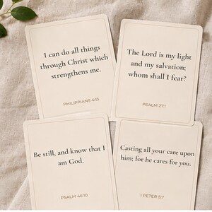 May include: Four rectangular off-white cards featuring black printed Bible verses. The cards display Philippians 4:13, Psalm 27:1, Psalm 46:10, and 1 Peter 5:7. Each card has a thin border and clear serif typography, arranged in a grid-like layout.