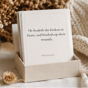 May include: A stack of rectangular white cards housed in a matching light beige box. The front card features the black printed text: He healeth the broken in heart, and bindeth up their wounds. PSALM 147:3. The cards have a thin light border.