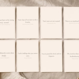 May include: Eight cream-coloured cards with inspirational quotes in a minimalist design. The cards feature phrases like "You do not have to be strong every second" and "Your tears are not wasted." The cards are arranged on a neutral-toned fabric.