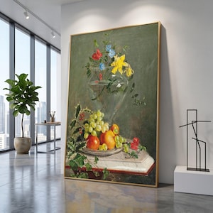 Puede incluir: Un cuadro vertical enmarcado con una pintura al óleo de naturaleza muerta. Un jarrón de cristal transparente contiene flores amarillas, rojas y azules. Debajo, un plato muestra uvas verdes, naranjas y manzanas rojas sobre un fondo verde oliva.