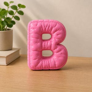 Close-up view of 3D rounded puffy letter STL models for 3D printing. Digital files shown as a colorless mesh to illustrate the 3D printable structure and smooth surface finish.