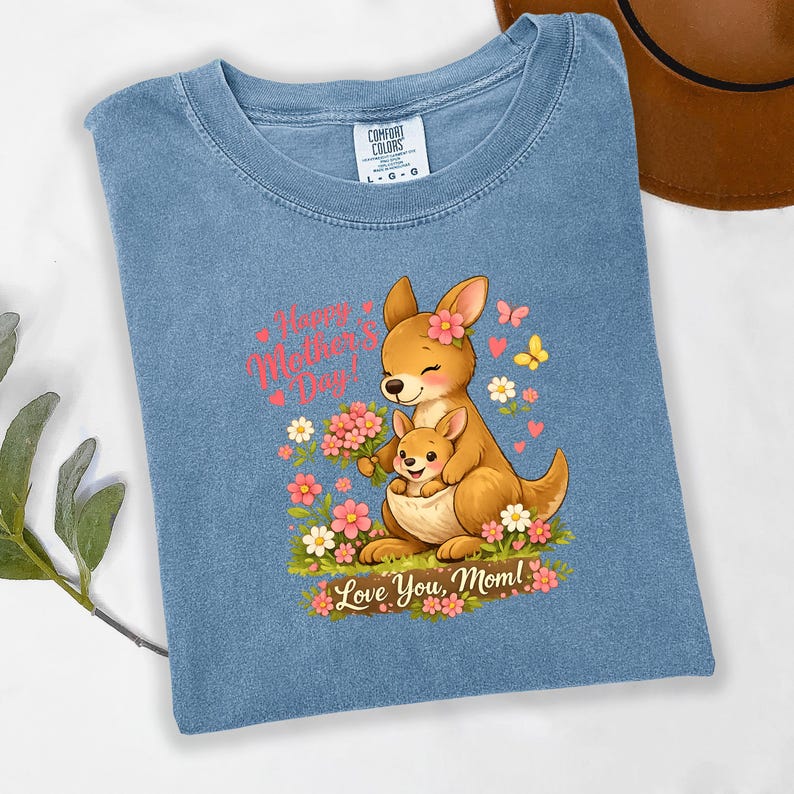 May include: A light blue t-shirt featuring a cartoon kangaroo with a joey in its pouch, surrounded by flowers and butterflies. The text "Happy Mother's Day!" and "Love You, Mom!" are displayed in pink.