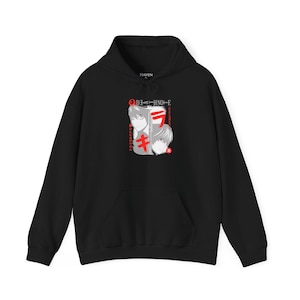 Puede incluir: Sudadera con capucha negra con un gráfico frontal que presenta ilustraciones de personajes de estilo anime en blanco y rojo. El diseño incluye texto japonés y un bolsillo de canguro. La sudadera tiene una capucha con cordón.
