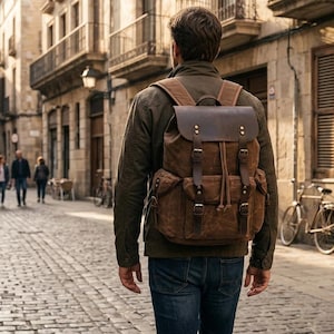 May include: A brown canvas and leather backpack with a top flap, two front pockets, and buckle closures. The bag features a drawstring opening and adjustable shoulder straps. The text Everyday & Travel Bag is visible in the bottom right corner.