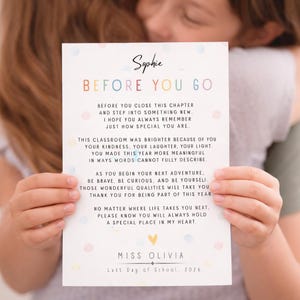 Puede incluir: Una tarjeta blanca con el texto "Sophie" y "BEFORE YOU GO" en letras coloridas. La tarjeta contiene un mensaje sincero sobre un año especial, firmado "Miss Olivia, Last Day of School, 2026".