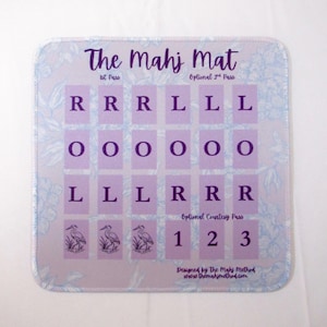 May include: A square Mahj Mat with rounded corners, featuring a light purple background with a faint blue floral pattern. The text reads The Mahj Mat, 1st Pass, Optional 2nd Pass, and Optional Courtesy Pass, with rows of letters R, O, L, and bird icons.