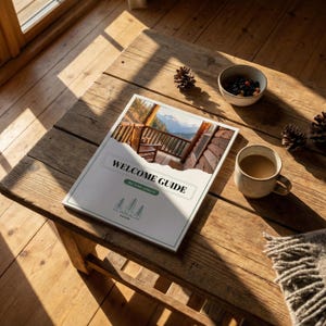 May include: A rustic wooden table with a "WELCOME GUIDE" booklet, a mug of coffee, a small bowl of berries, pine cones, and a cozy blanket. The booklet features a cabin scene and the text "WELCOME GUIDE".