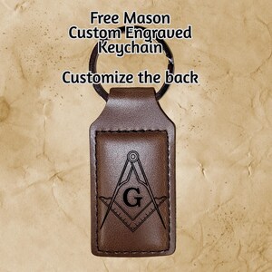 May include: Brown leather keychain with a metal ring. The keychain features a rectangular leather tag with the Free Mason symbol and the text "Free Mason Custom Engraved Keychain" and "Customize the back".