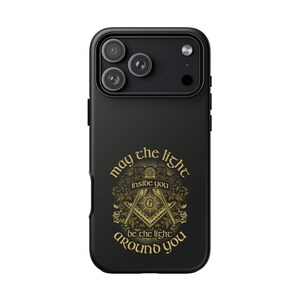May include: Black phone case featuring a gold Masonic emblem and the inscription "may the light inside you be the light around you." The design incorporates a square and compass symbol.