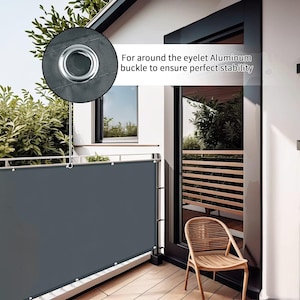 Könnte beinhalten: Ein dunkelgrauer Balkon-Sichtschutz mit einem kreisförmigen Einsatz, der eine Nahaufnahme einer silbernen Aluminiumöse zeigt. Der Text For around the eyelet Aluminum buckle to ensure perfect stability ist auf dem Sichtschutz aufgedruckt.