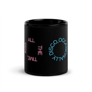 Peut inclure: Mug en céramique noire avec le texte "Kiss All The Time, Occasionally Disco" en rose et bleu. Le mug a une finition brillante et une forme cylindrique. Le texte est disposé verticalement et en cercle.