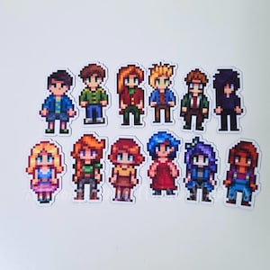 May include: A collection of twelve pixel art stickers featuring diverse characters with varied hair colors, including blonde, red, blue, and black, wearing different outfits like shirts, skirts, and overalls, arranged in two rows on a white surface.