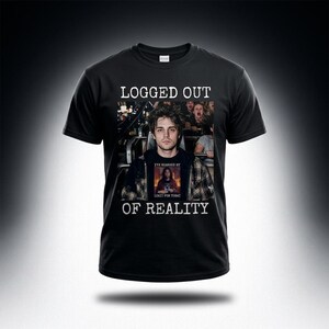 Op de afbeelding: Zwart t-shirt met de witte tekst "LOGGED OUT OF REALITY". Het shirt heeft een foto van een persoon in een attractie, met een kleinere afbeelding op hun shirt met de tekst "I'VE REACHED MY LIMIT FOR TODAY".