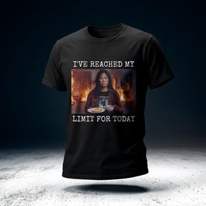 Op de afbeelding: Zwart t-shirt met de tekst "I'VE REACHED MY LIMIT FOR TODAY". Het shirt heeft een afbeelding van een persoon in een keuken met vlammen op de achtergrond. De persoon houdt een bord met eten en een kopje vast.