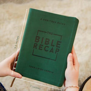以下が含まれることがあります： 「The Bible Recap」というタイトルの緑色のハードカバー本。著者の名前はTara-Leigh Cobble。本の高さは24cm、幅は18cm。「A One-Year Guide」というテキストが上部にあります。