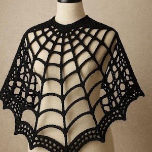 May include: A black crochet poncho featuring an openwork spiderweb pattern. The garment has a round neckline and a pointed, scalloped hemline that extends outward from the center, creating a distinct web-like structure across the shoulders.