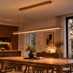 Pode incluir: Uma luminária pendente linear de madeira suspensa por dois cabos metálicos finos a partir de um suporte de teto retangular de madeira, com uma longa fita de LED integrada que emite uma luz quente sobre uma mesa de jantar.