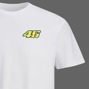 May include: White t-shirt with the number "46" in yellow with a black outline. The number is on the upper left chest. The shirt has a crew neck and short sleeves. The fabric appears to be cotton.