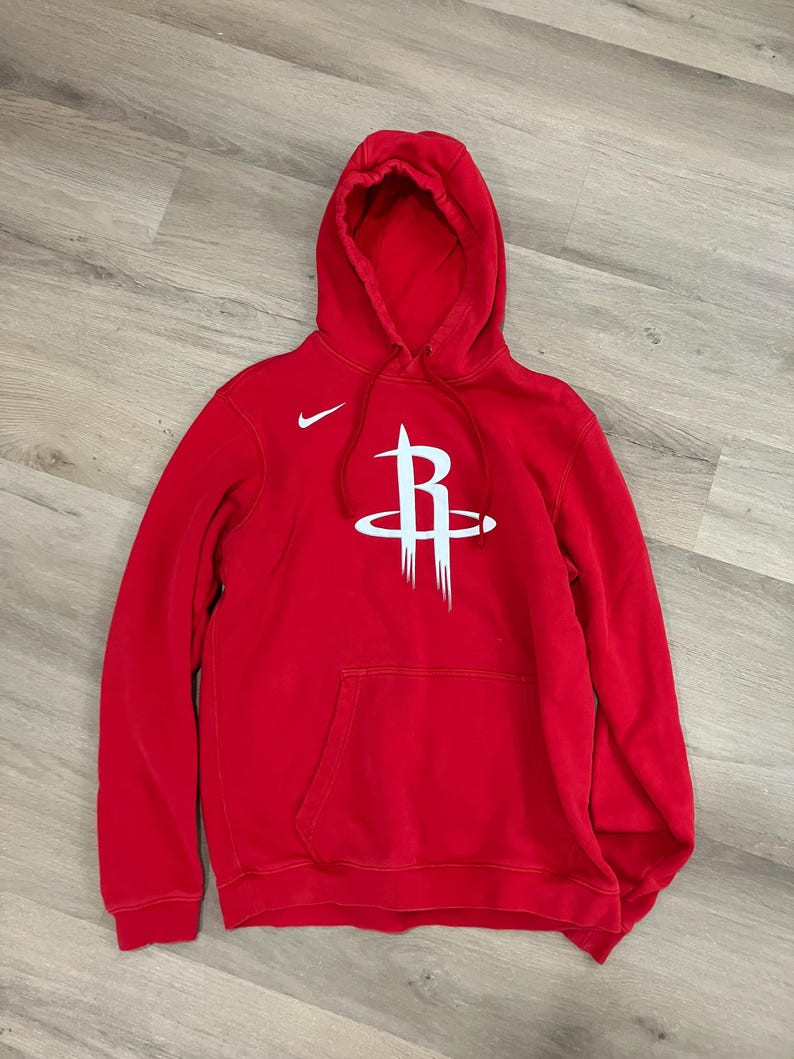 Puede incluir: Sudadera con capucha roja con el logotipo blanco de los Houston Rockets en la parte delantera. Cuenta con una capucha con cordones, un bolsillo delantero y un peque&ntilde;o logotipo blanco de Nike. La sudadera est&aacute; hecha de un material suave.
