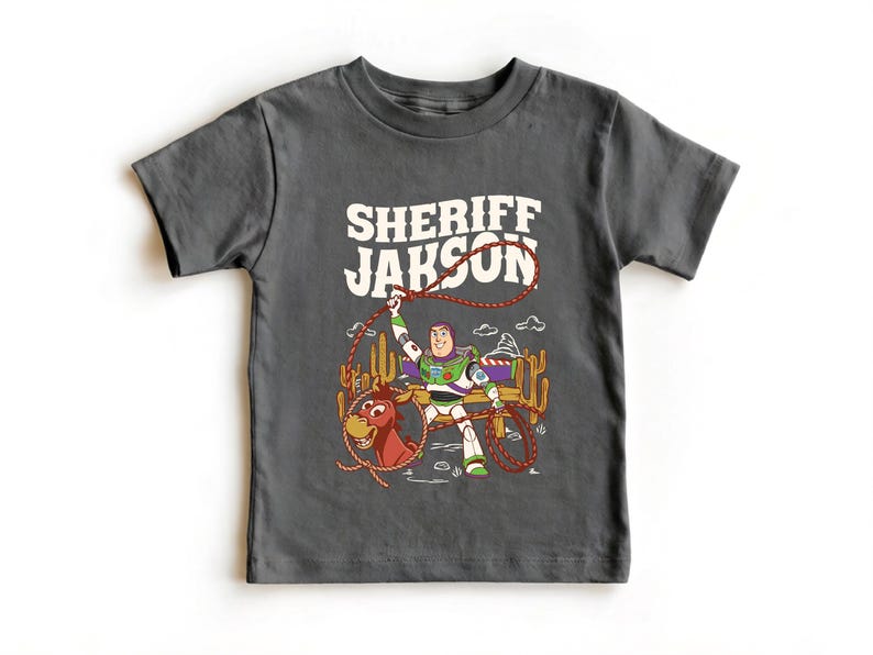 Personalized Sheriff Shirt, Custom Deputy Name T-Shirt, Space Ranger Cowboy Tee, Kids Western Birthday Gift, Toddler Buzz Lightyear Shirt

Step into an adventure-filled world for your little hero! This custom-designed t-shirt blends a beloved space-themed character with a fun western twist, sparking your child's imagination. It is the perfect outfit for birthday parties and a stylish choice for everyday playtime.