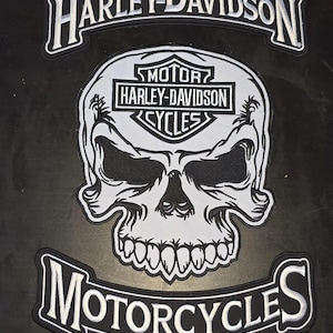 May include: Black and white Harley-Davidson Motorcycles patch featuring a skull design. The patch has the Harley-Davidson logo at the top and the word "Motorcycles" at the bottom. The skull has large eye sockets and a row of teeth.