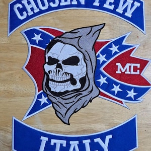 Puede incluir: Parche bordado con una calavera con capucha, con las palabras "CHOSEN FEW" e "ITALY" en blanco sobre pancartas azules. El diseño incluye elementos rojos y azules con estrellas y las letras "MC".