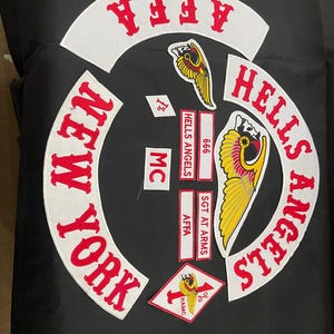 May include: A collection of embroidered patches featuring the words "HELLS ANGELS" and "NEW YORK" in red lettering on white arched backgrounds. Additional patches include "AFFA", "MC", and a winged skull logo.