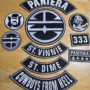 May include: A collection of black and white embroidered patches featuring band logos and text. The patches include the band name "Pantera", "St. Vinnie", "St. Dime", and "Cowboys From Hell". Some patches have additional graphics.