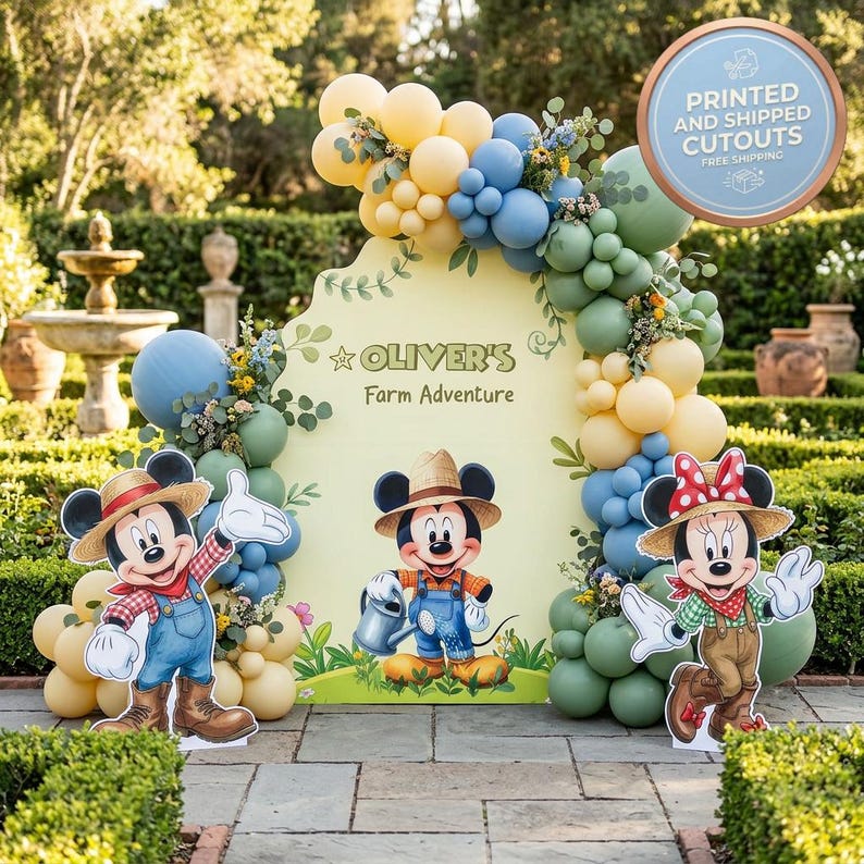 May include: A large yellow event backdrop featuring the text "OLIVER'S Farm Adventure" and illustrations of Mickey and Minnie Mouse in farm attire. The display is decorated with a balloon arch in shades of yellow, blue, and sage green.